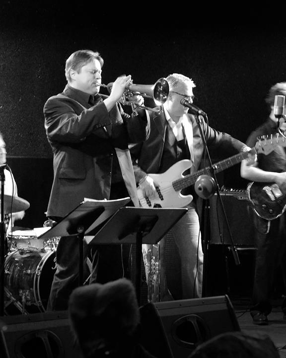 Michael Paul playing trumpet on stage with his band